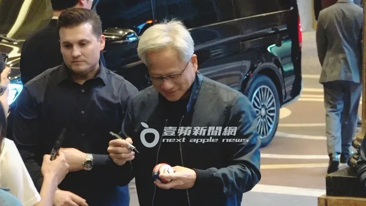 黃仁勳專心幫粉絲簽棒球。特勤中心攝