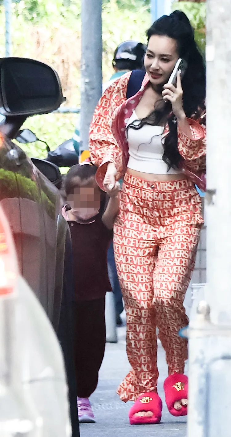 王思佳一手牽女兒，一手忙著講電話（女兒衣服經變色處理）。特勤中心攝