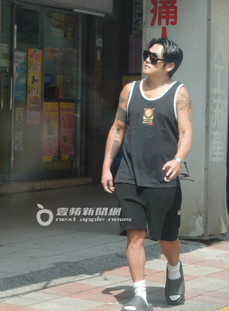 曹格穿著拖鞋走在東湖路上，不時四處張望附近建築物。特勤中心攝