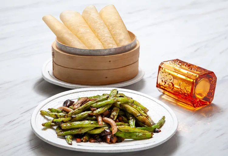 經典粵式小炒的創新詮釋「欖菜松柳煸四季豆」（420元），主廚加入北方吃法搭配餅皮包卷，提升層次。四季豆煸至乾香爽口，拌以鹹鮮欖菜與菇類快炒，素食也能鮮香誘人，清爽富口感。台北凱撒大飯店提供