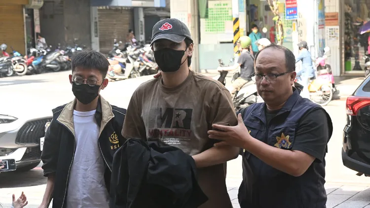 陳零九涉逃避兵役下午遭警方拘提到案，他戴著帽子口罩，手上包裹著衣服疑似被上銬，被警員帶入警局問訊。翻攝畫面