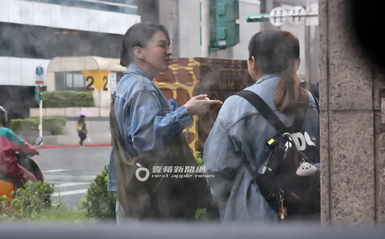 當天下著小雨，張榕容（左）不畏被淋濕，站在路邊與助理等車。特勤中心攝