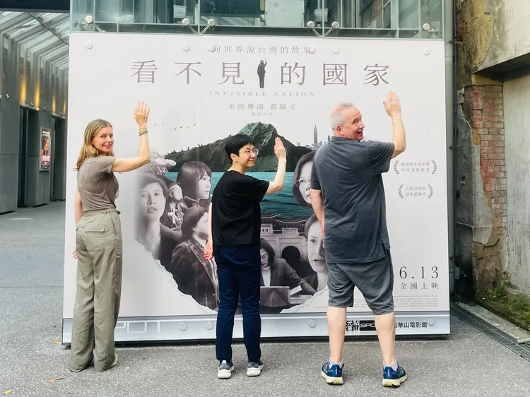 導演葛靜文（左）、配樂許瑋珊與製片泰德霍普在跑映後空檔開心在電影海報牆前留影。
