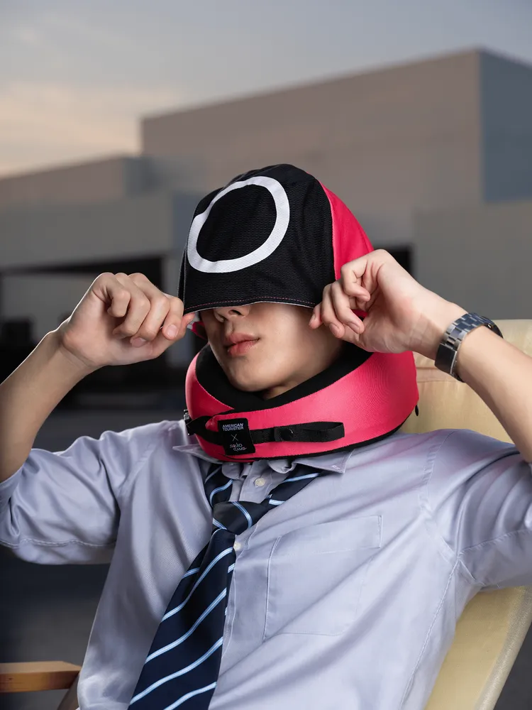 旅行頸枕內藏有《魷魚遊戲》粉紅衛兵造型的網布帽，可拉起作為輕遮光面罩。品牌提供