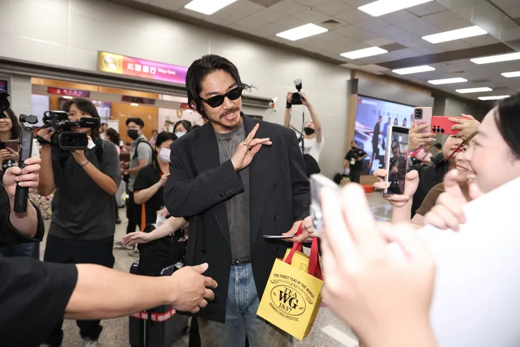 AKIRA滿手禮物和粉絲送的信，不忘揮手打招呼。彭欣偉攝