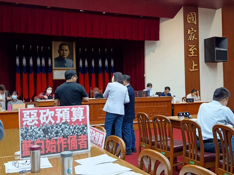 立法院財政委員會今（4日）審查民眾黨團提案「要求行政院立即足額撥付一般性補助款」，多位立委爆口角，會議現場擺放「惡砍預算，藍白始作俑者」、「預算已三讀公布，今日會議，違法違憲」等抗議板。許麗珍攝