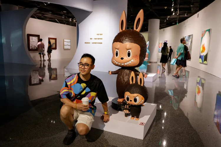 棕色的限量版拉布布玩偶也拍出高價，民眾在拍賣前的展示會與玩偶合影。路透社