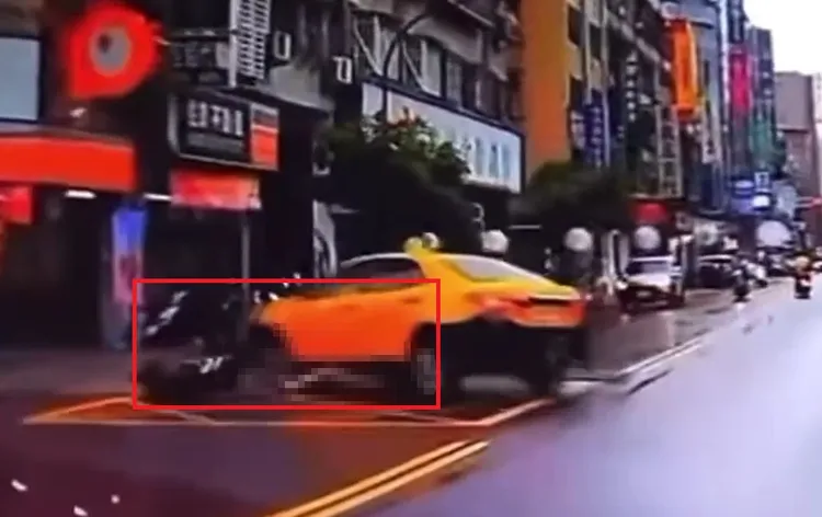 騎士滑倒後遭左轉的計程車輾過。翻攝畫面