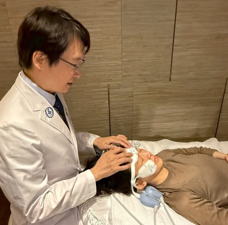 黃勇學總院長正在為顧客貼EMFACE菲斯波貼片