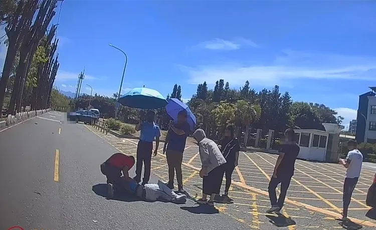 熱心民眾替倒地不起的機車騎士撐傘遮陽。民眾提供