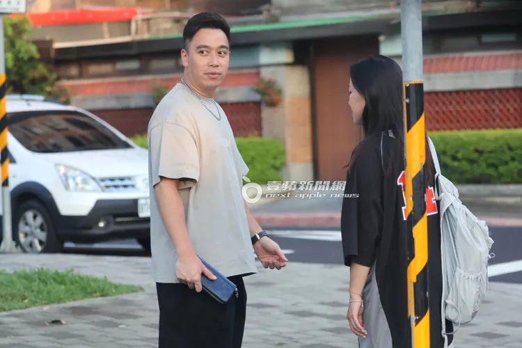 無尊（左）手拿深藍色LV長皮夾，和小麥色皮膚女子在路邊聊天。特勤中心攝