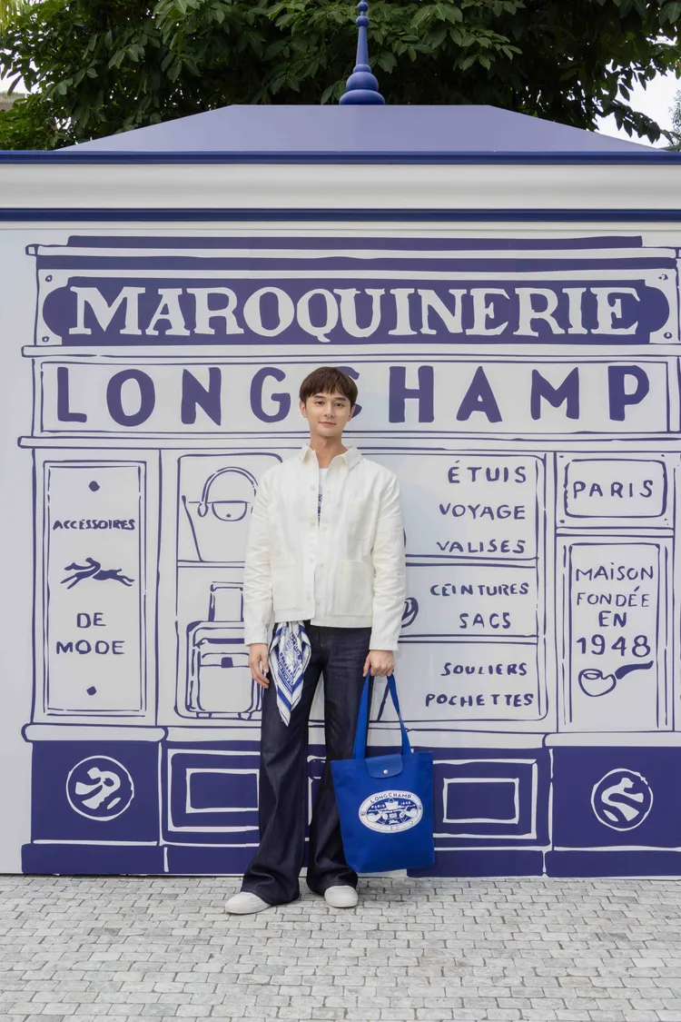 張軒睿身穿聯名系列T-shirt及米白色外套，並以絲巾點綴穿搭。品牌提供