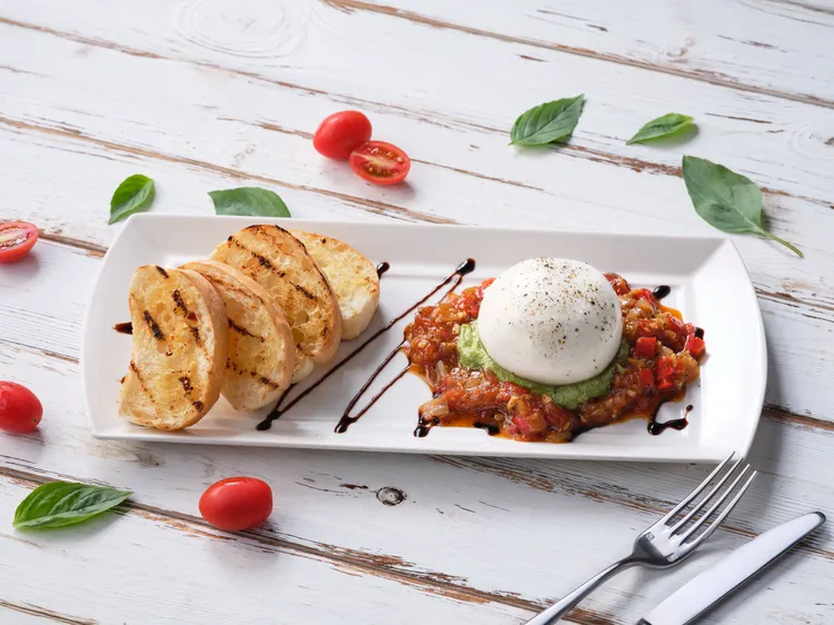 TGI FRIDAYS推出多款令人驚喜的料理，「烤番茄布拉塔」酸甜滋味適合初夏時節。業者提供