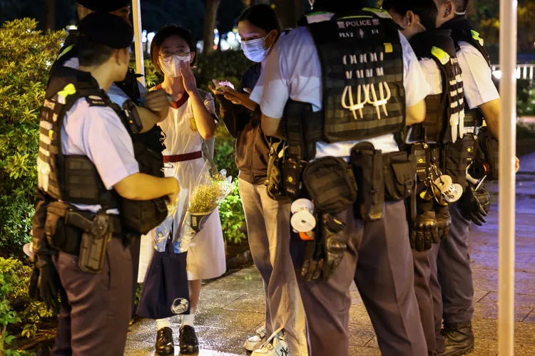 帶著白色花束的女學生遭香港警察攔下盤問。路透社