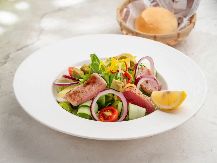 「鮪魚酪梨沙拉」些微炙煎表面的肥美鮪魚片，加上豐富生菜與滑順酪梨切塊，再以滋味香濃的奶油餐包收尾，清爽與飽足兼具，是「逸起放暑假」夏季國人住房專案的七月限定餐點。台北中山九昱希爾頓逸林酒店提供