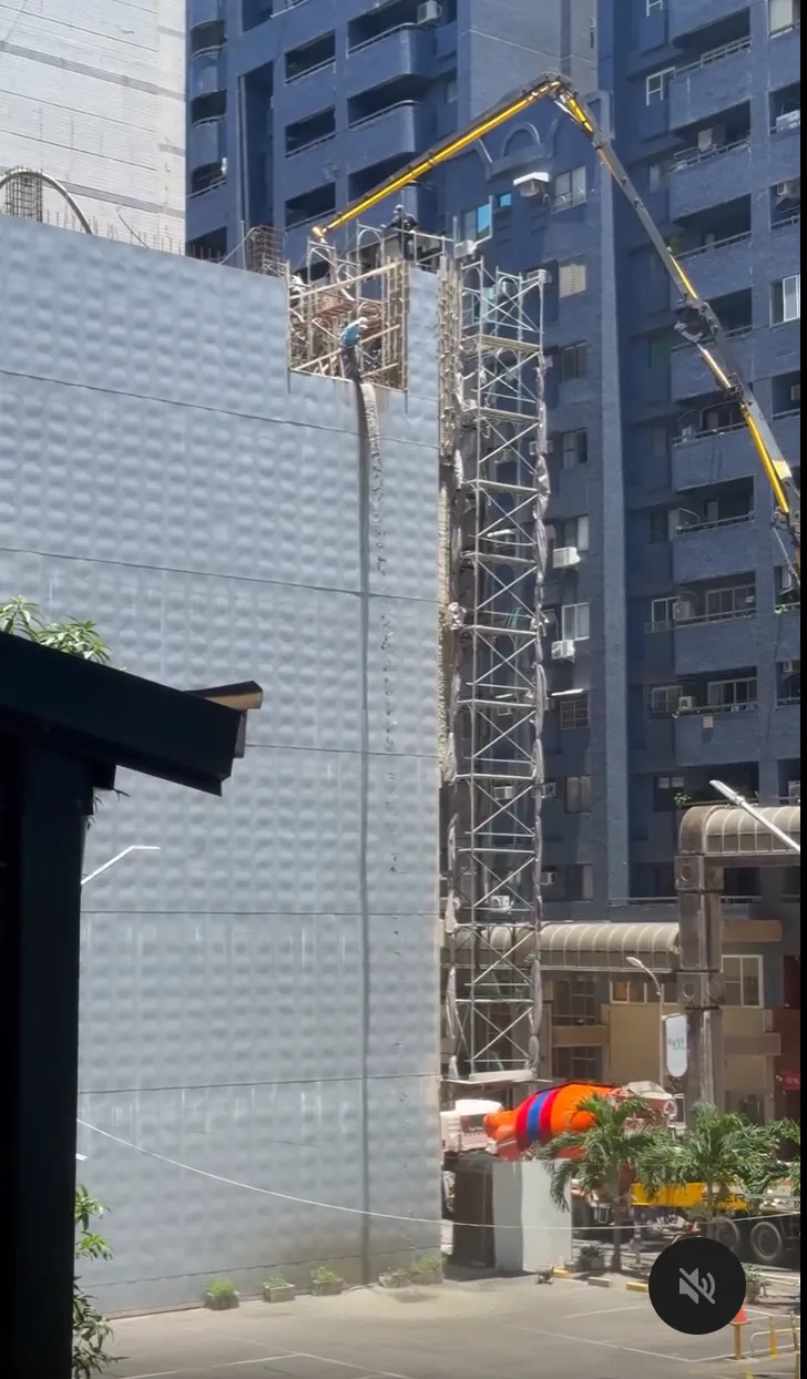 建築工地23日因灌漿速度控制不當，導致水泥不斷從頂樓傾瀉而下。翻攝threads畫面