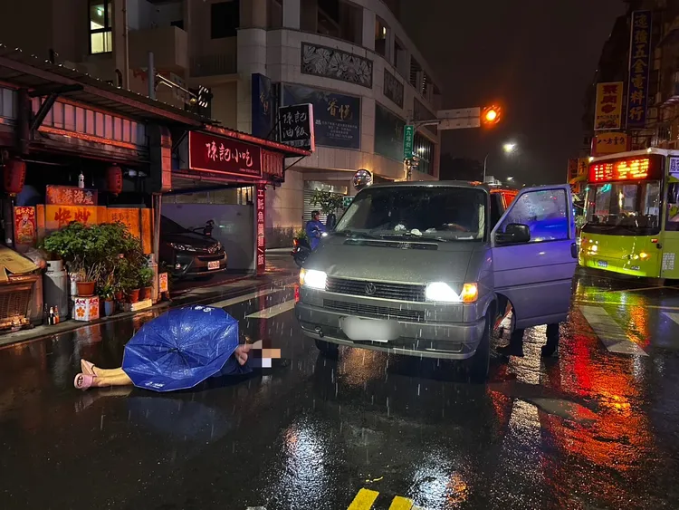 被撞傷婦人獨留現場無法動彈，只好躺在路中間等待救援，一旁還有掉落的雨傘。翻攝畫面