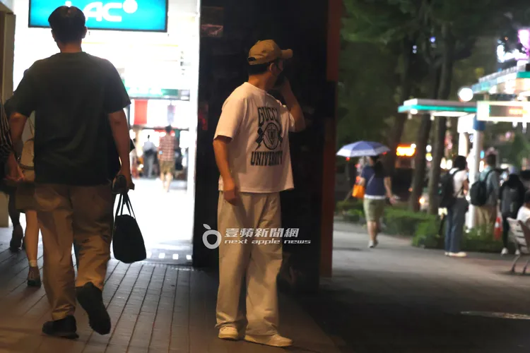 李進良在診所外頭講電話，不時回頭查看，似乎在尋找車輛。特勤中心攝