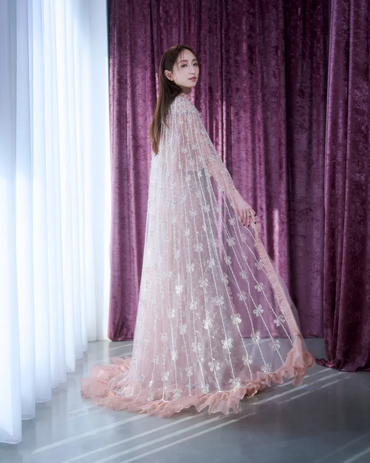 披肩以透明薄紗拼接粉色薄紗，並以蝴蝶結串珠點綴出華麗又靈動的樣貌。品牌提供