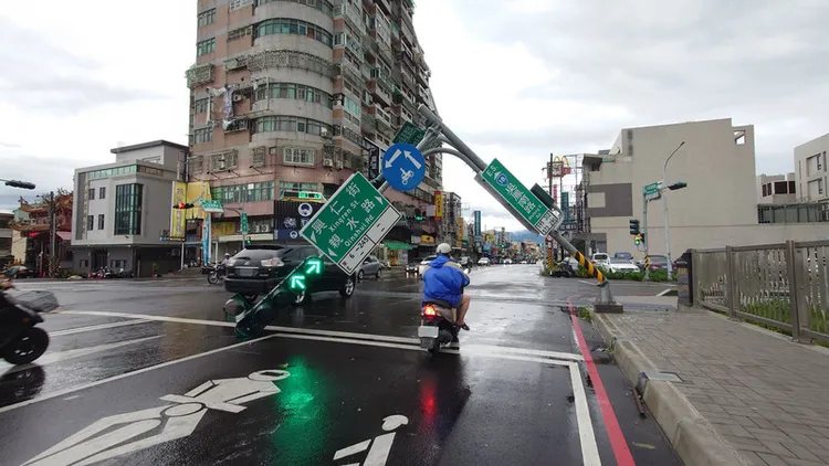 颱風丹娜絲襲台為嘉義帶來強烈風雨，7日嘉義市軍輝橋路口的紅綠燈倒伏，民眾冒險從下方騎車通過。 中央社