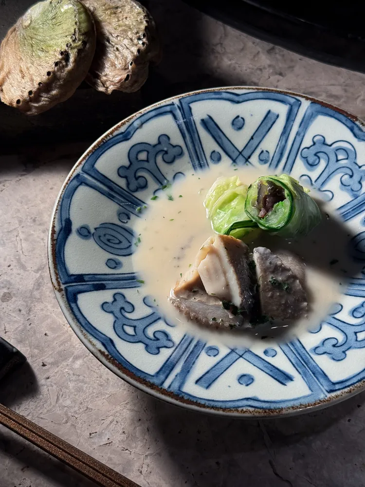 主菜「鮑魚」搭配雲林清燉甲魚製成的高麗菜捲，以龍虎斑熬成的白湯串接，蔬菜與海味的鮮甜形成「1+1>2」的鮮味加乘效果。豊漁餐飲集團提供