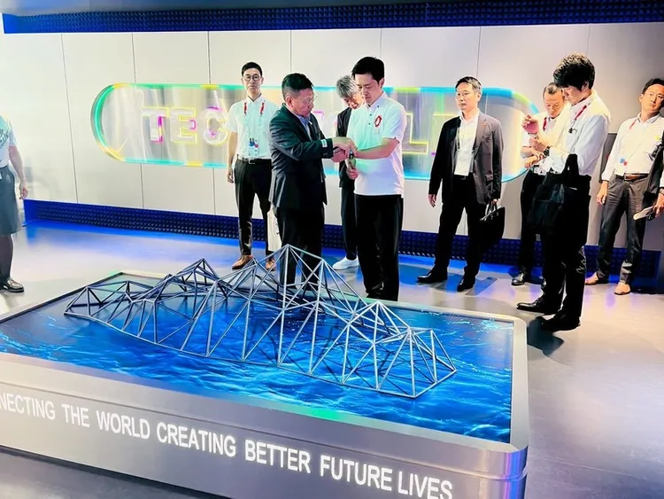 大阪府知事吉村洋文（右）26日造訪大阪世博TECH WORLD館，在正式參觀之前，由館長邱揮立（左）協助配戴智慧手環。 （TECH WORLD館提供） 中央社