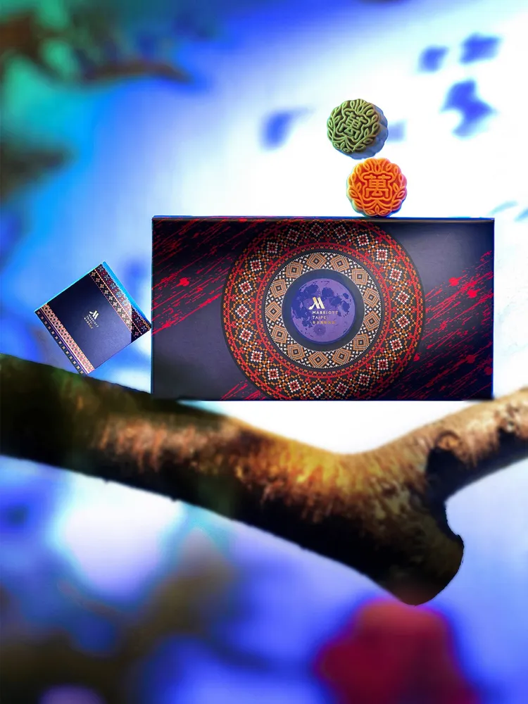 台北萬豪酒店「萬月」果茶十光月餅禮盒，盒身設計以獨特視角重新詮釋中秋團圓意象，融合生肖蛇年的靈動優雅與台灣原住民圖騰的文化底蘊，將傳統節慶賦予當代藝術靈魂，交錯輪轉的同心圓寓意團圓與永續美好。業者提供