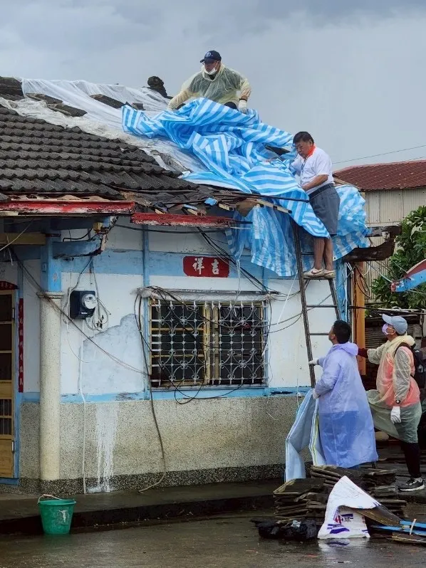 屏東縣社會處青年志工爬上屋頂協助遮蓋帆布。翻攝畫面