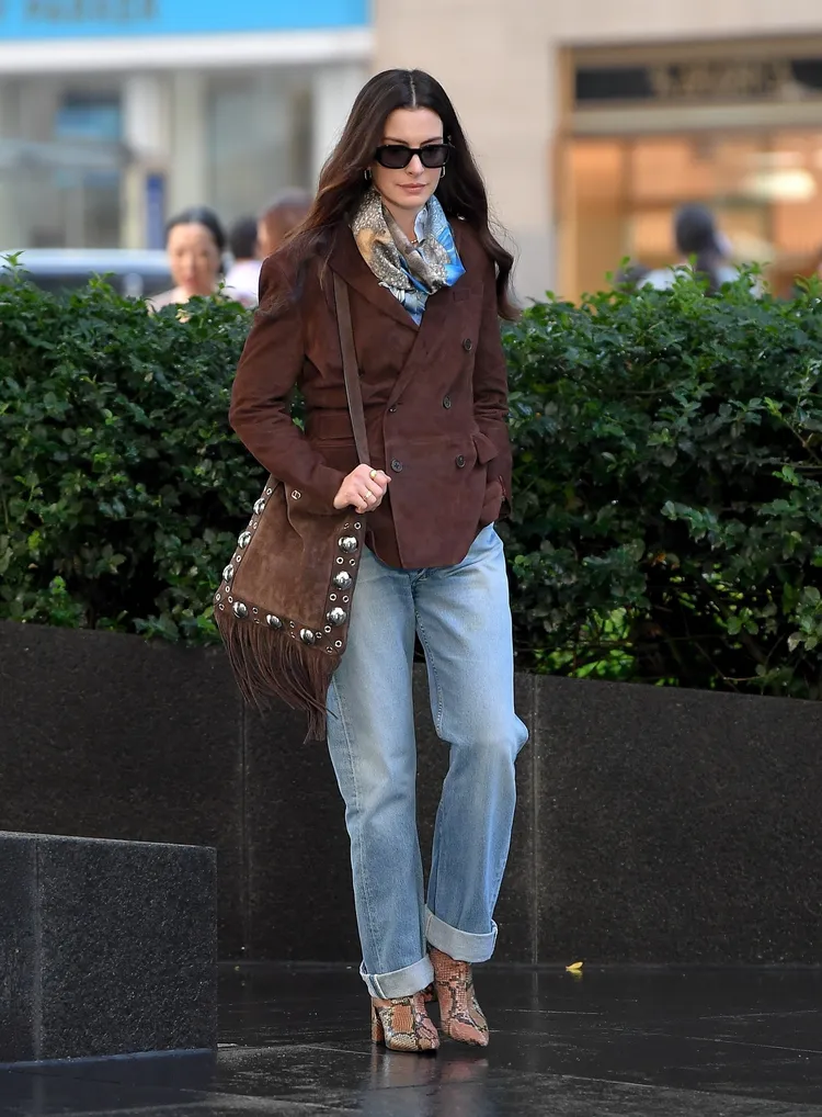 安海瑟薇以深褐色雙排扣西裝外套搭配Valentino Garavani Nellcôte包款。品牌提供