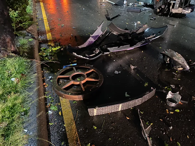 自小客車撞上浮起的人孔蓋側翻，地上滿是零件碎片。民眾提供