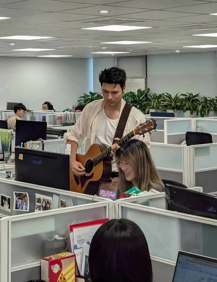 鳳小岳首次體驗當上班族 對女同事放電彈吉他。硬柿子工作室提供