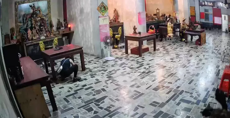 犯嫌蹲在神桌下偷取錢母。翻攝照片
