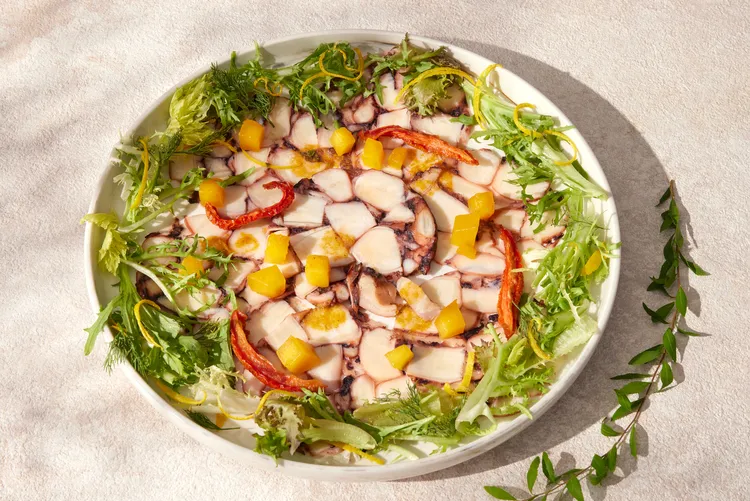 「慢煮章魚薄片、西西里醬」南義風味的經典開胃菜，選用新鮮肥美的章魚，以低溫燉煮3小時候冷藏塑形。定型後的章魚捲切成薄片，搭配生菜與主廚特製的清爽芒果油醋醬。台北喜來登大飯店提供