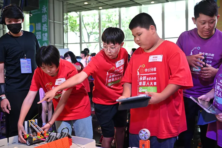 2025永齡希望小學機器人大賽比賽現場，孩子們穿上隊服、揮舞隊旗，投入比賽現場。永齡基金會提供