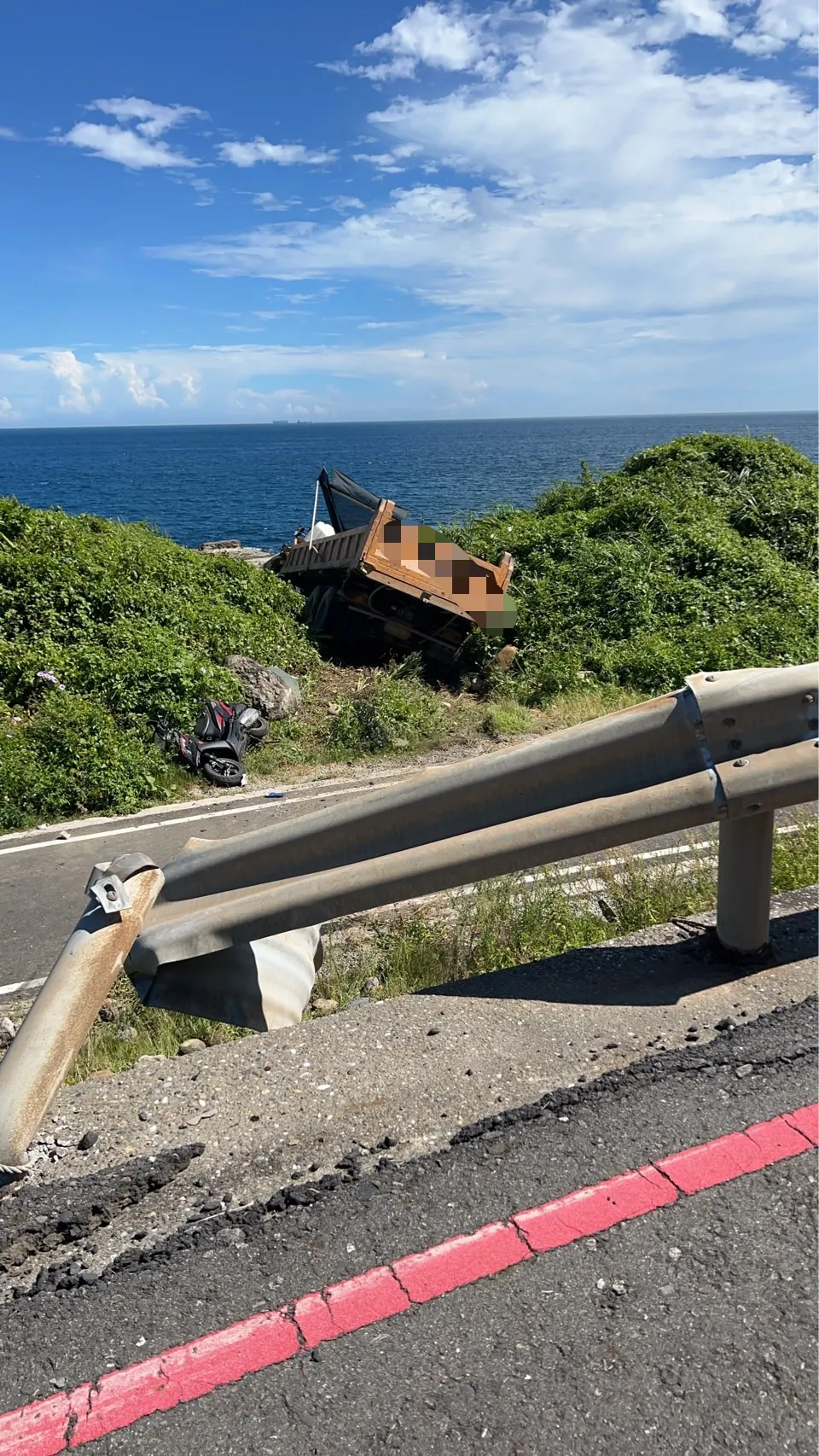 砂石车失控冲出道路,直至卡进草丛后才停下。翻摄照片