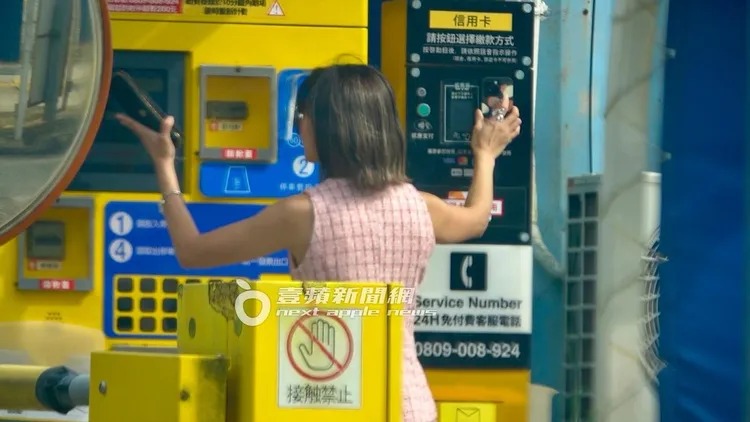 大牙雙手並用繳停車費，一手忙著按螢幕，一手拿手機支付感應。特勤中心攝