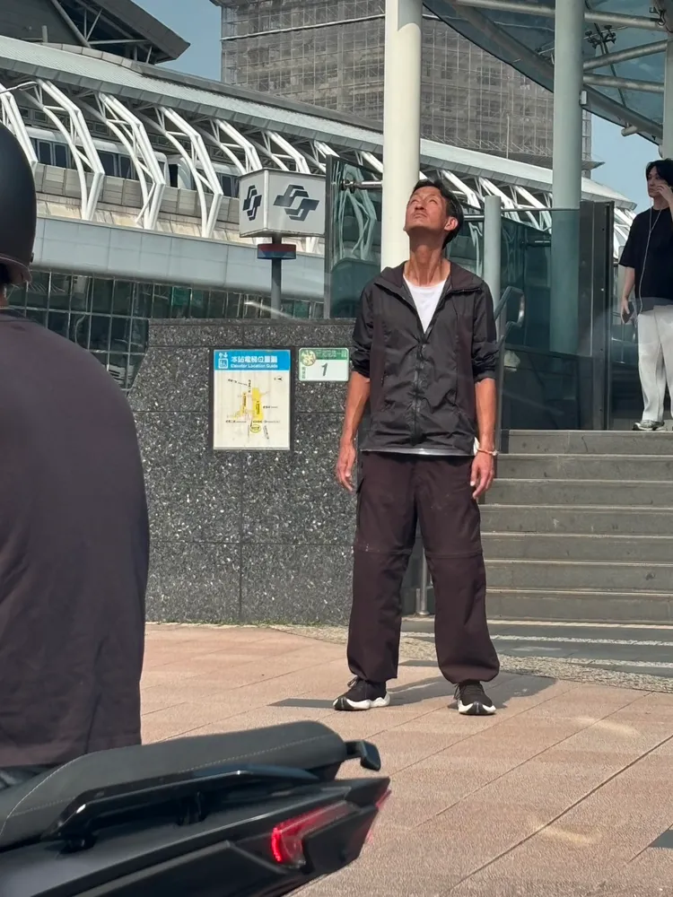 唐治平大熱天穿著長袖外套站在豔陽下運動，眼神空洞。讀者提供