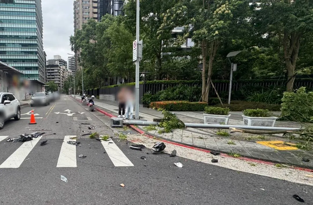 车祸现场灯杆倒地,车壳零件散落,一度交通受阻。翻摄画面