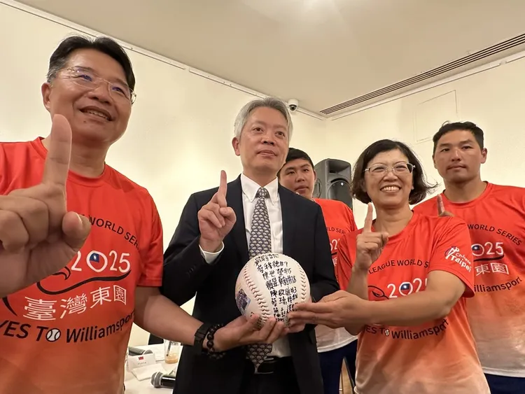 駐紐約辦事處長李志強（左2）拿出東園國小少棒隊10年前到訪的簽名球，與校長張鍾榮（左1）、前校長陳毓卿（右2）和「帥一下」教練駱政宇（右1）合影。 中央社