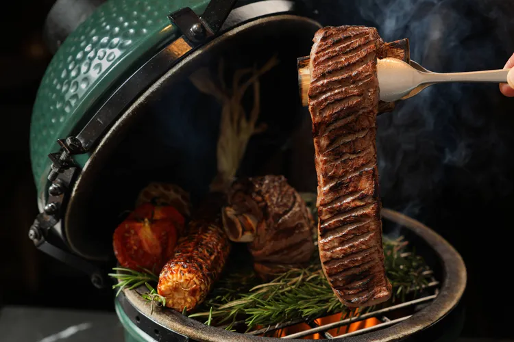 ROBIN’S牛排屋享用「愛你入骨．繾綣帶骨牛」套餐，主廚會先以豪邁的直火炭烤激發帶骨牛小排的油脂香氣，出餐前再以特殊爐具煙燻，展現爆發的視覺效果。台北晶華提供