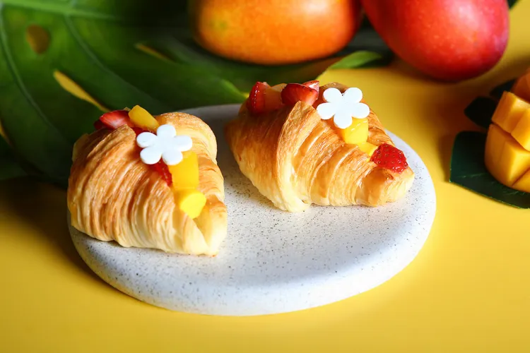 台北萬豪Lobby Lounge「芒芒仲夏」下午茶，「新鮮芒果冰可頌」將新鮮芒果泥、檸檬汁製成義式冰淇淋，夾入酥脆可頌中，再以新鮮草莓及芒果丁裝飾，多層次口感令人驚喜。業者提供