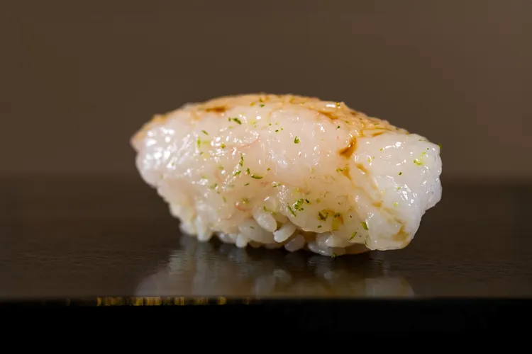 富山小白蝦握壽司選用來自富山灣的珍貴小白蝦，經日本進口無味胡麻油輕拌，撒上德島酸橘皮，再以紫蘇葉包裹捏製，是海洋純淨與日式細膩的味覺詩篇。業者提供