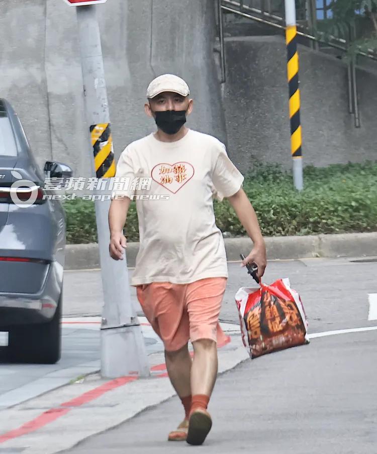 黃子佼戴貝雷帽、口罩遮臉，身穿「加油囍事」T恤、橘色短褲配紅襪、踩金色拖鞋。特勤中心攝