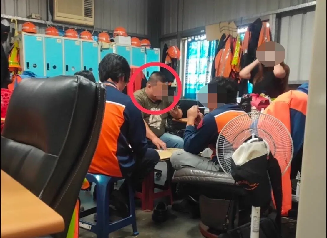 穿著橘色制服的清洁队同仁,坐在沙发围成一圈,跟著林姓班长(图中灰色T恤)一起玩牌。民众提供