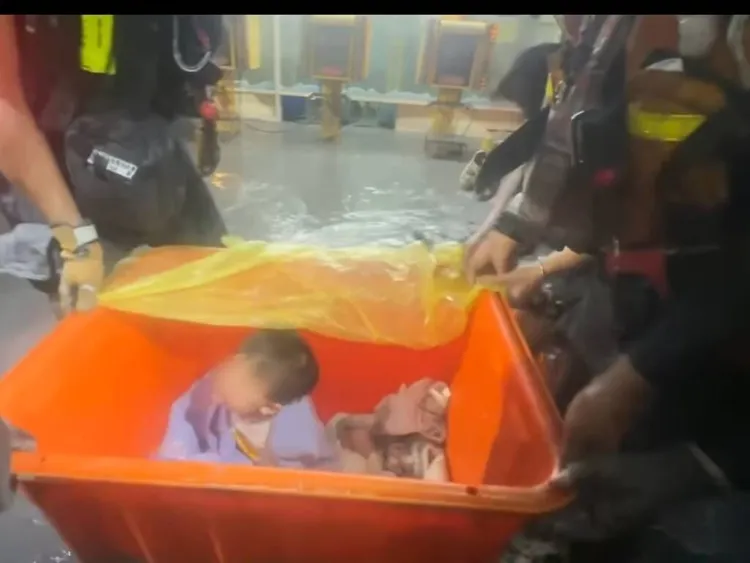 搜救人員涉水用大水桶裝著2名幼童協助脫困。翻攝畫面
