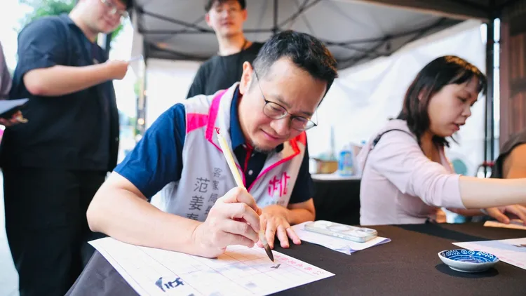 客家局長范姜泰基現場體驗書法活動，揮毫感受傳統文化魅力。客家局提供