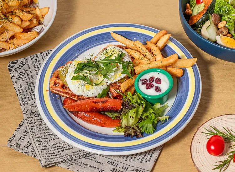 「酪梨熱壓可頌」外酥內軟的可頌層疊新鮮酪梨醬、水波蛋與芝麻葉，搭配德式香腸、油醋沙拉、優格與薯條，兼具營養與口感。業者提供