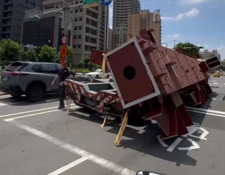 聯結車後方鋼柱傾斜掉落，翻覆於路中間，恰好就擋住機車待等區，騎士經過拍下過程。民眾提供