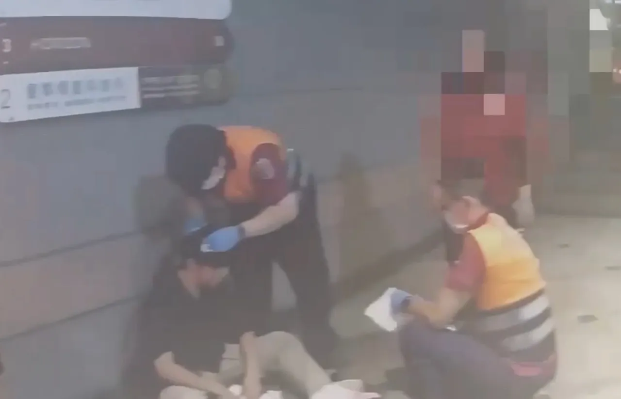22岁萧姓台大硕士生被打破头,血溅当场,无力地靠著一旁墙壁,医护人员正忙著帮他止血。翻摄画面