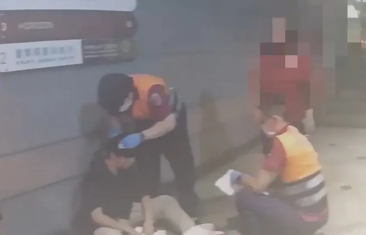 22歲蕭姓台大碩士生被打破頭，血濺當場，無力地靠著一旁牆壁，醫護人員正忙著幫他止血。翻攝畫面